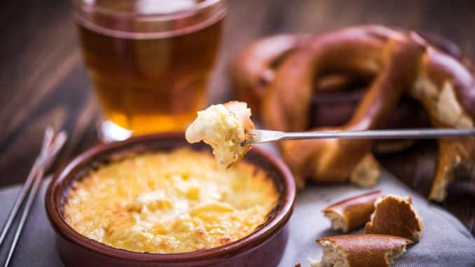 60870414 - worming cheese fondue with pretzel at winter evening